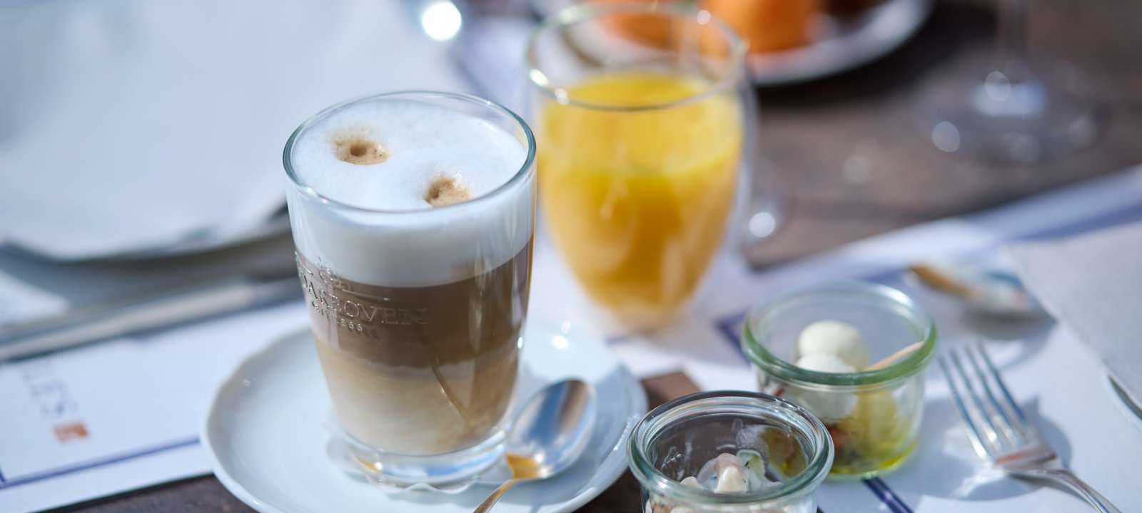 Frau vom Service deckt einen Tisch zum Frühstück mit Geschirr ein auf der Terrasse