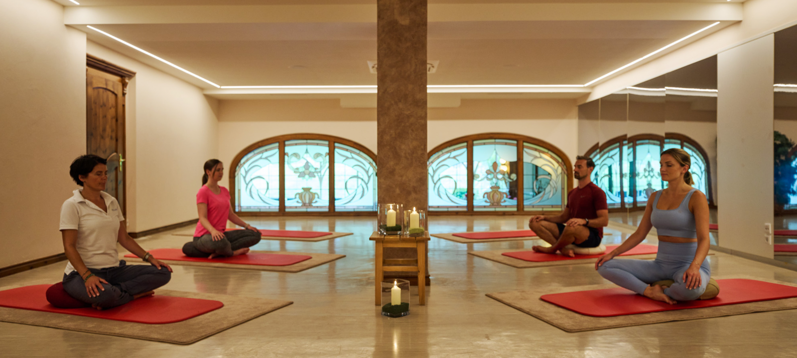 Gymnastikraum mit vier Menschen die meditieren