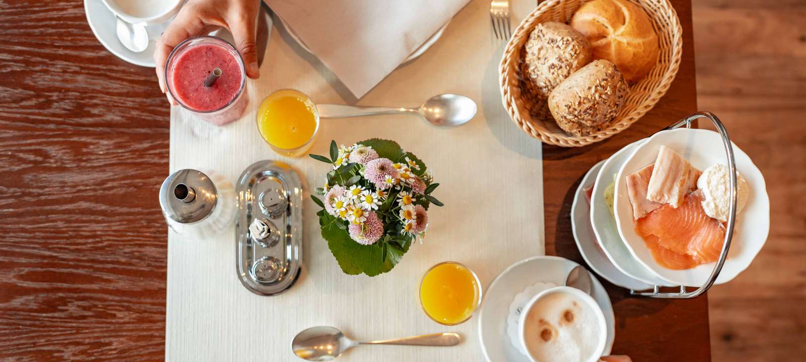 Frau vom Service deckt einen Tisch zum Frühstück mit Geschirr ein auf der Terrasse