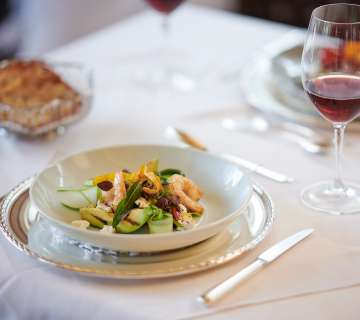 Gedeckter Tisch mit maritimem Essen und einem Glas Rotwein