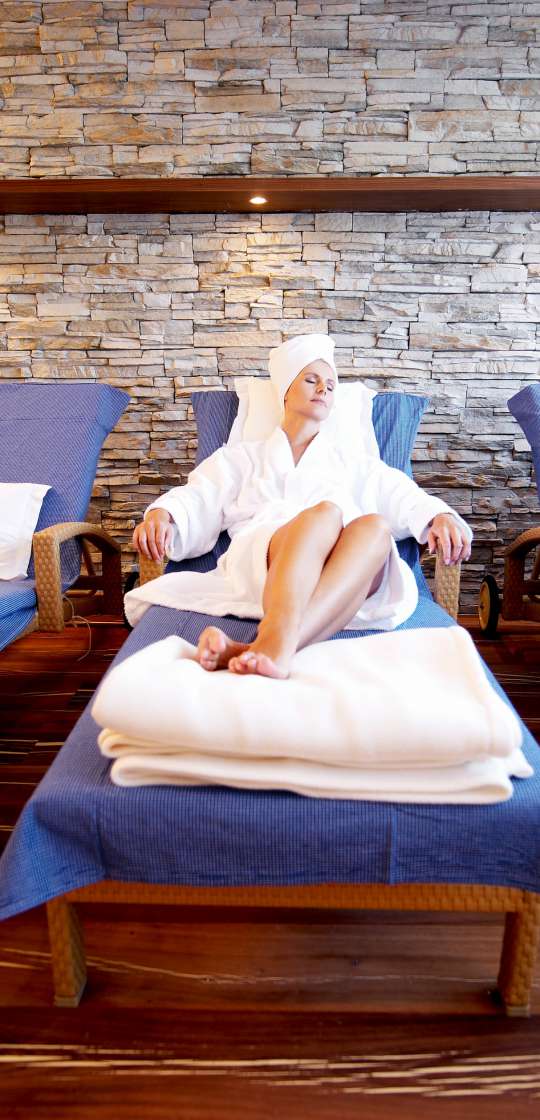 Frau liegt im Bademantel auf Ruheliege