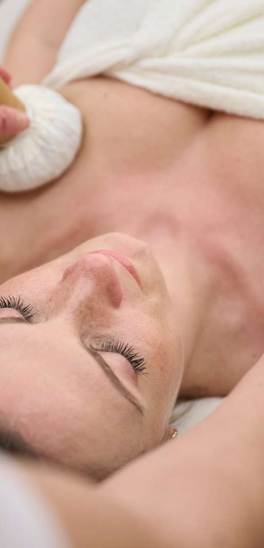 Frau bekommt Kräuterstempel Massage