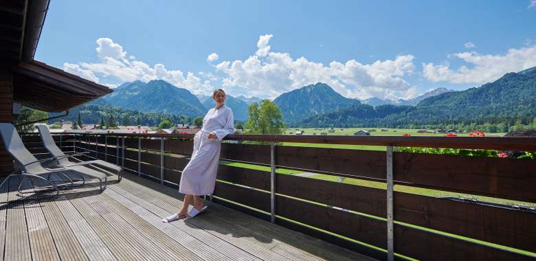 Frau in Bademantel genießt frische Luft auf Panoramabalkon im Ladies Spa