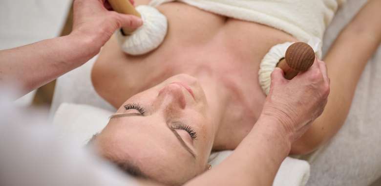 Frau bekommt Kräuterstempel Massage